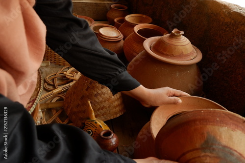 Close-up of tourist hands holding and inspecting handcrafted ceramic earthenware vessel