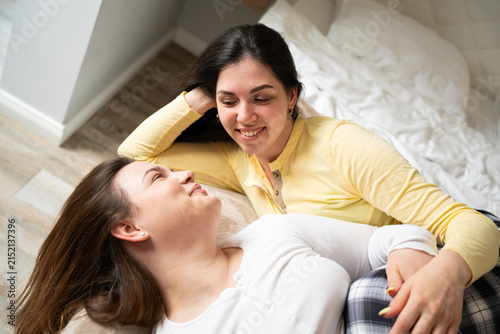 Konstfotografi Two women relaxing together on a cozy bed in a warmly lit home interior