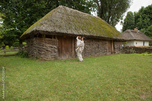 Traditional Ukrainian thatched roof house with a child climbing the wall