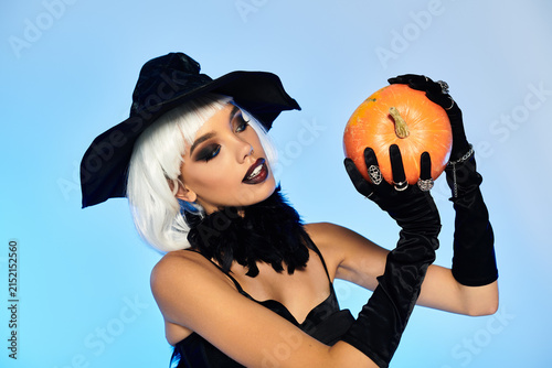 Obraz na płótnie Glamorous witch with a bob cut and pumpkin in a studio for Halloween fun