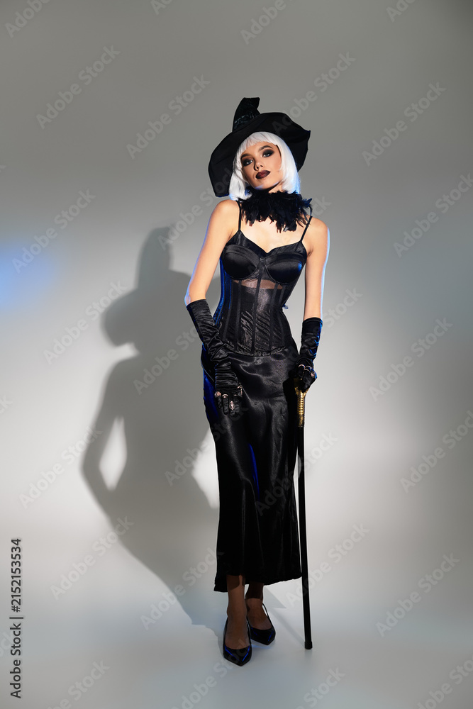 Obraz premium Glamorous witch in a stunning costume poses playfully in the studio