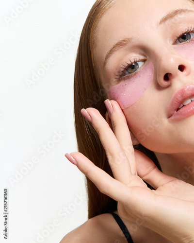 A happy young woman with face patches poses on a light background