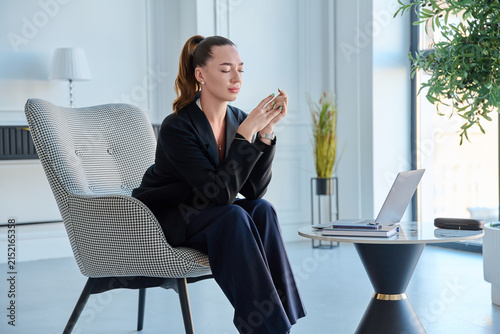 Stressed businesswoman sitting with eyes closed rubbing hands near laptop