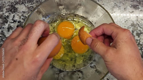 Mano rompiendo un huevo fresco en un recipiente de vidrio