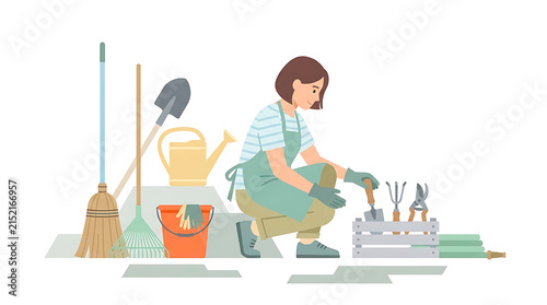 Young woman gardener wearing apron and gloves working in the garden with various tools and equipment