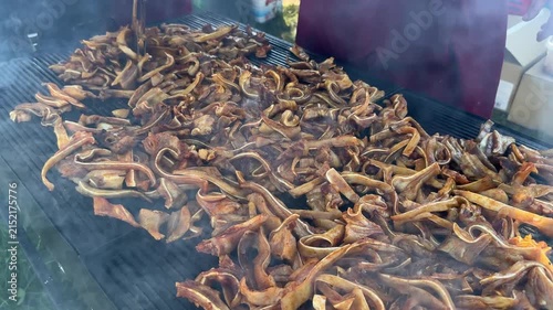Chef grilling traditional sliced pig ears on outdoor barbecue grill
