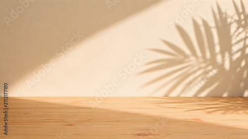 Minimalist wooden table surface with soft natural light and tropical plant shadow on beige wall.