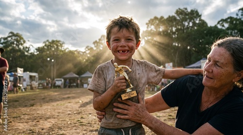 Happy boy holding a small gold sports trophy award outdoors at sunset