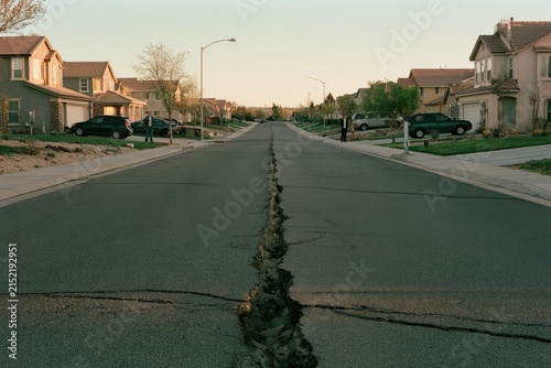Conceptual scene of a suburban street split by a deep crack, with two neighbors on opposite sides, symbolizing polarization and social division.