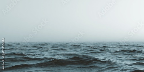 Vast dark ocean waves roll beneath a heavy blanket of thick gray fog creating a minimalist and moody atmosphere that evokes deep feelings of calm isolation, minimal seascape with horizon