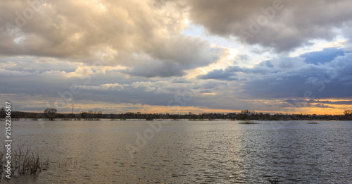 Dramatic clouds above reflective lake at golden hour