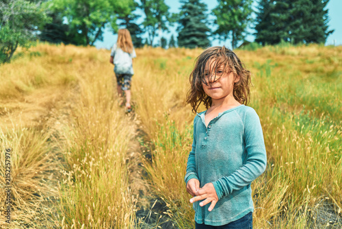 Two boys on a hillside path through tall golden grass