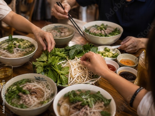 Gemeinsames Essen mit Pho am Tisch – Mehrere Schüsseln vietnamesischer Nudelsuppe mit frischen Kräutern und Beilagen, eine authentische Szene für Familie, Freunde und Genussmomente.