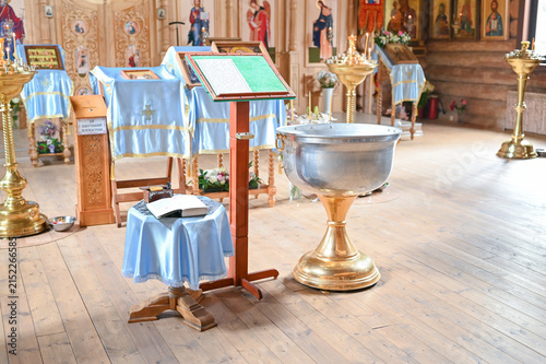 Obraz na plátne Silver baptismal font, lectern, iconostasis inside a traditional wooden Orthodox church prepared for a baptism ceremony