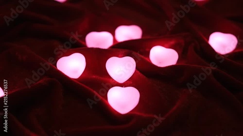 Glowing heart shaped lights resting on a soft dark red fabric
