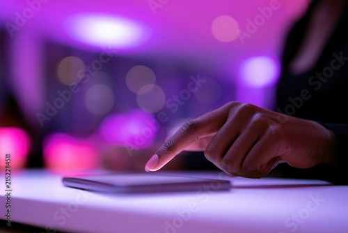 Human hand Use mobile phone illuminated trendy cinematic neon lights. Hands of Teen Girl scrolling up photos at dark night room. Internet browsing. Close-up finger. Social media. Digital lifestyle