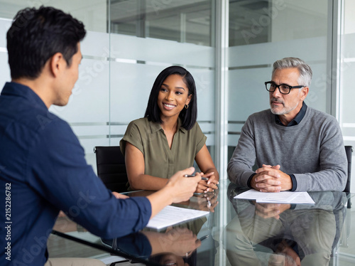 Diverse business professionals engaged in an important discussion, reviewing documents in a modern office setting.