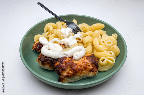 Baked chicken breast with elbow macaroni pasta and creamy garlic sauce in a green ceramic bowl