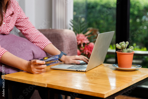 Female using credit card and laptop for online payment at home. Internet banking, online shopping, and secure digital transaction business concept.