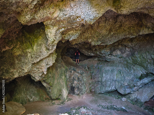 Fotografie Hiker standing inside a rocky passage of Három-kúti Cave, surrounded by rugged limestone formations in the Bükk Mountains, Hungary