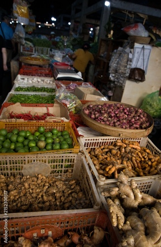 Obraz na plátně Assorted fresh spices and ingredients like galangal, ginger, turmeric, limes, and chilies displayed in plastic crates at a traditional local market in Bali, Indonesia