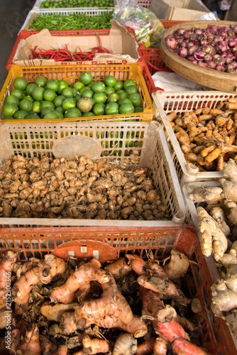 Fotografie Assorted fresh spices and ingredients like galangal, ginger, turmeric, limes, and chilies displayed in plastic crates at a traditional local market in Bali, Indonesia