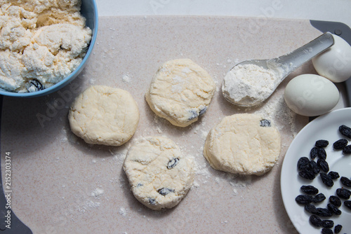 Raw cottage cheese pancakes on a cutting board. Bake ingredient, eggs, flour, raisins. Preparing for breakfast. Top view.