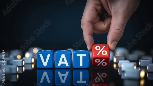 Hand placing a red percent sign cube next to blue vat letter cubes on a dark reflective surface representing tax rate calculation and financial