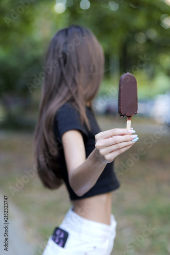 Young woman holding chocolate ice cream popsicle outdoors