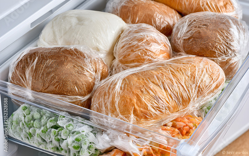 A loaf of wheat bread and other frozen food on a shelf of a home freezer, big procurement and food storage in reserve. Frozen bread.