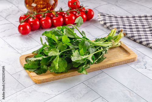 Foto Fresh cilantro on wooden cutting board with cherry tomatoes and olive oil