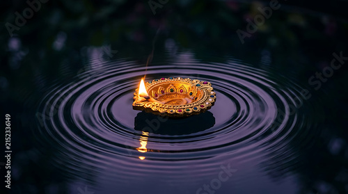 A beautiful glowing diya lamp floating on dark water with ripples creating a serene atmosphere