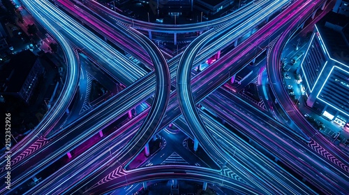 Aerial view of illuminated highway interchange with neon blue and purple traffic light trails