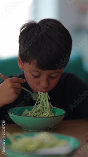 Photography Boy eating spaghetti with fork at family table, enjoying healthy nutrition, inde