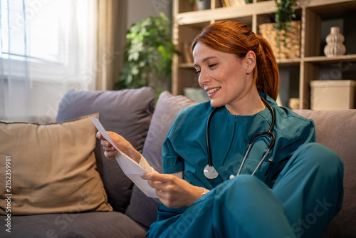 Foto Nurse in scrubs relaxing at home reading letter