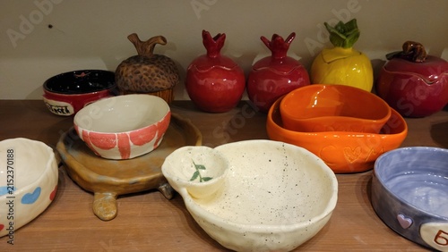 Colorful handmade ceramic dishes displayed on shelf in pottery studio