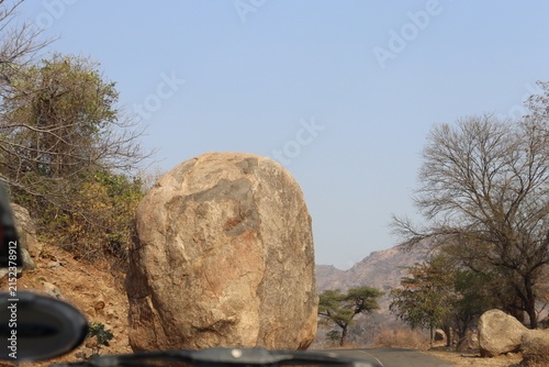 Fotografie Scenic semi-arid mountainous landscape featuring rugged rocky hills, dry woodland, scattered trees, large natural boulders and a tranquil reservoir surrounded by rolling terrain