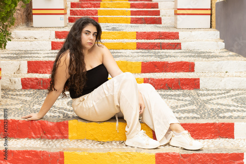 Young woman sitting on colorful stairs in calpe, spain