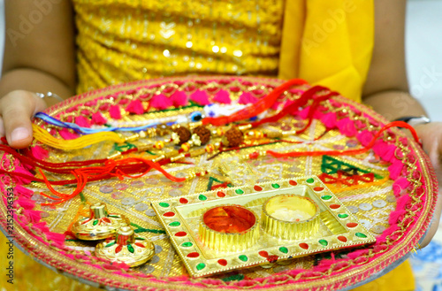 Raksha Bandhan thali with rakhi, rice, kumkum and sweets on a de