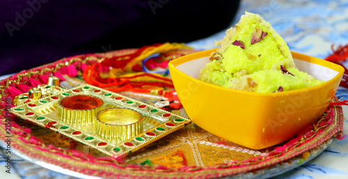 Raksha Bandhan thali with rakhi, rice, kumkum and sweets on a de