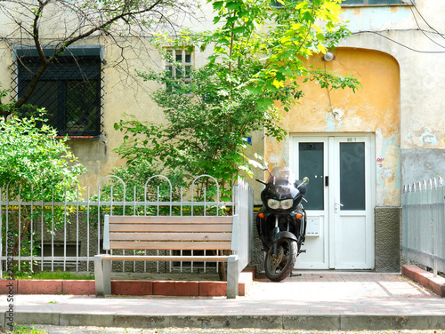 Motorcycle parked near entrance of old block of apartments in Bucharest