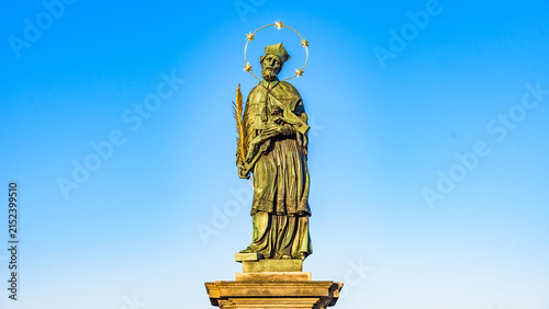 Statue of St John of Nepomuk on Charles Bridge in Prague, Czechia, UNESCO World Heritage Site, against clear blue sky