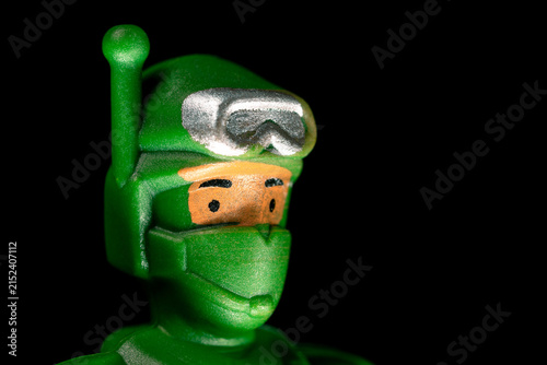 Green plastic toy soldier head with helmet and goggles close up