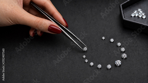 Elegant Hand Examining Diamonds with Jeweler’s Tweezers