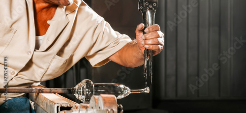 Glassblower Shaping Molten Glass Article in Workshop