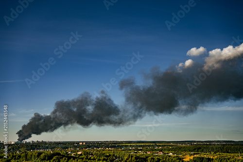 Cuadro en lienzo Black smoke billowing from a warehouse fire creating a dark plume against the bl