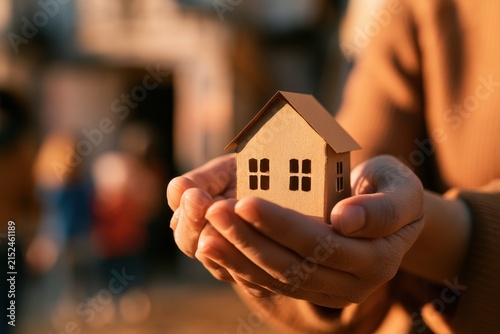 Close-up of a paper house held by caring hands representing family stability, foster care, and shelter programs