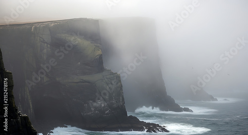Misty coastal cliffs during a foggy morning with crashing waves below
