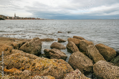 Algae and mussels covered stones at Edinburgh beach, overcast sky in background