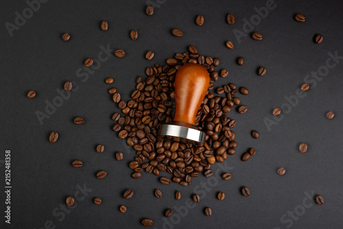 Принти на полотні Coffee tamper and scattered roasted beans on a dark background